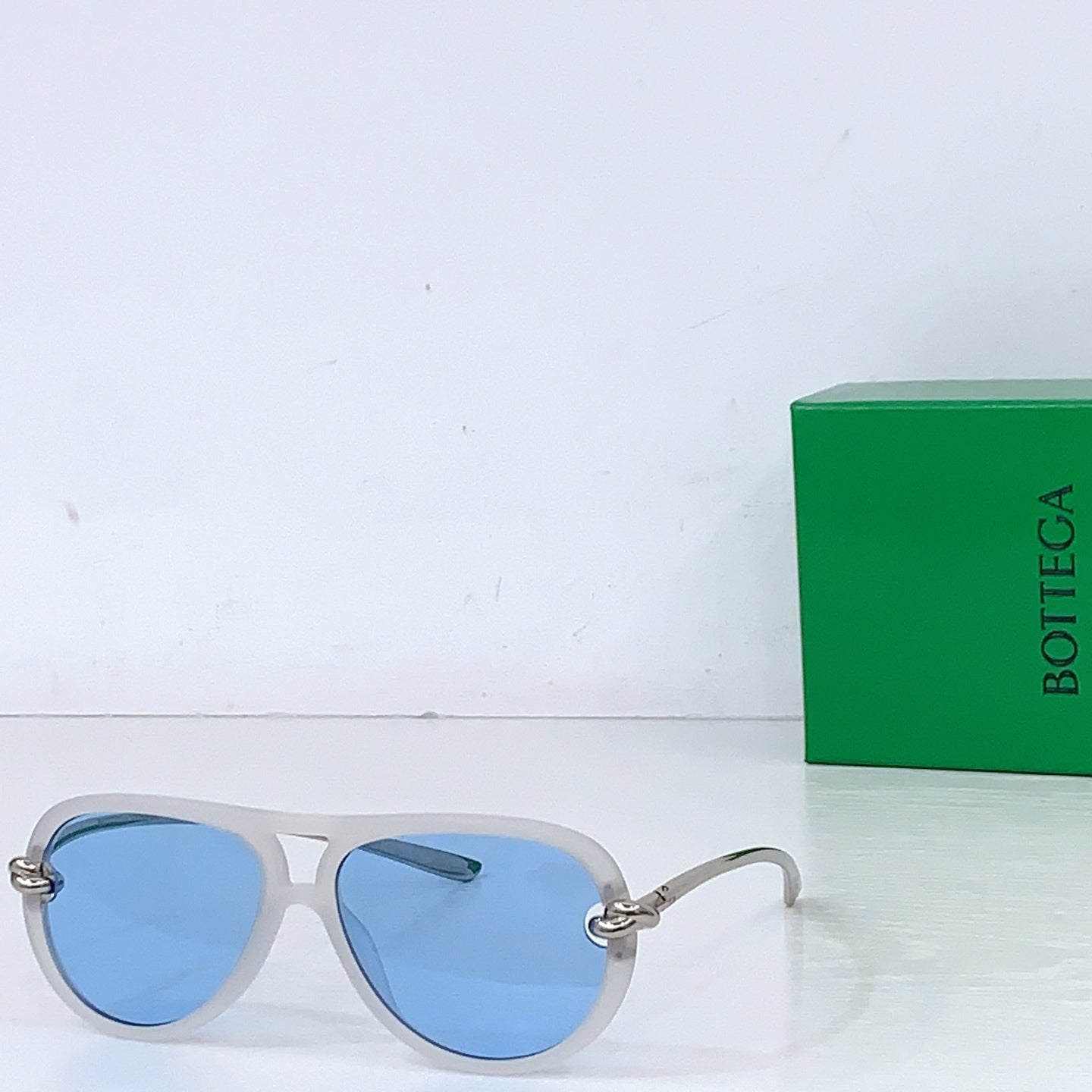 Bottega Veneta sunglasses, light gray frames with blue-tinted lenses and gold-tone hinges