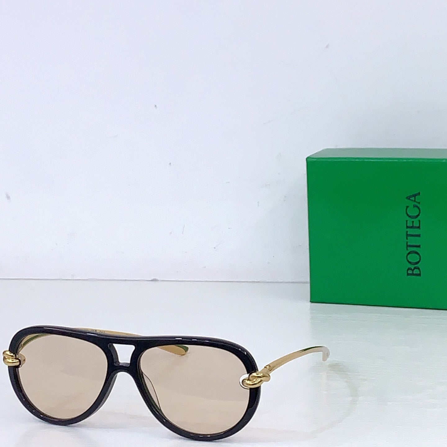 Bottega Veneta sunglasses, dark frames with light tan lenses and gold-tone hinges