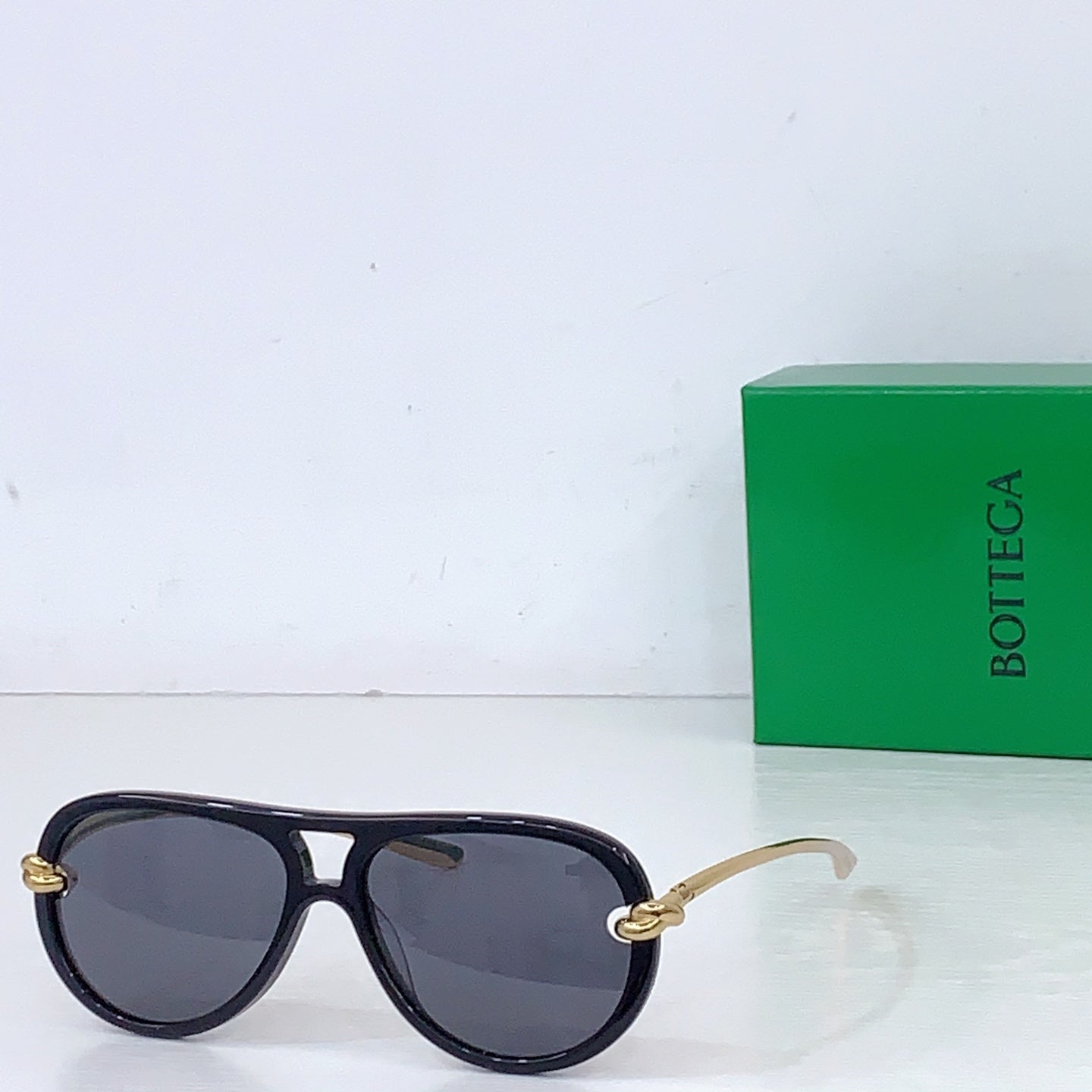 Bottega Veneta sunglasses with dark frames and blue-gray lenses, gold-tone temple details