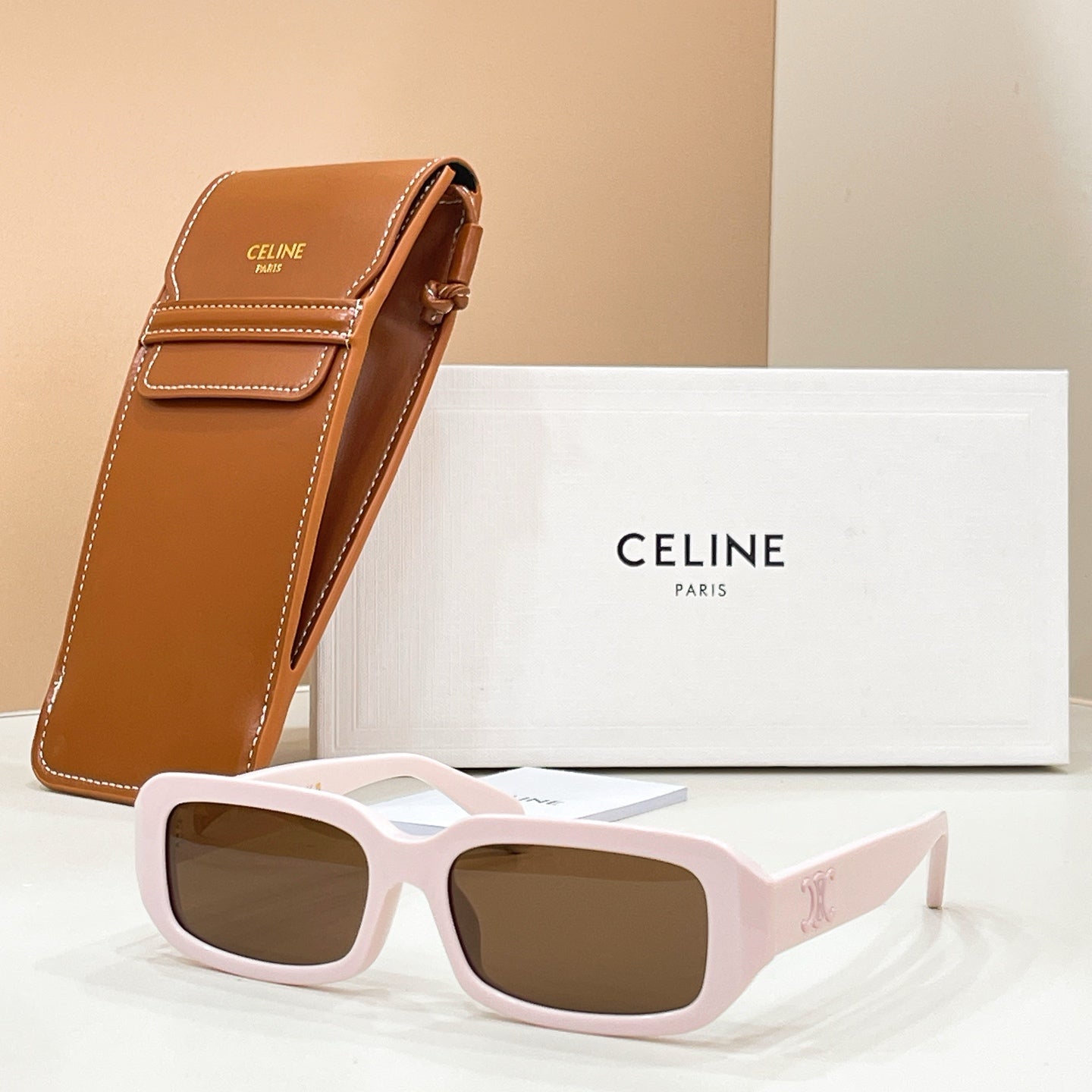 Celine sunglasses with light pink frames and brown-tinted lenses, with tan case