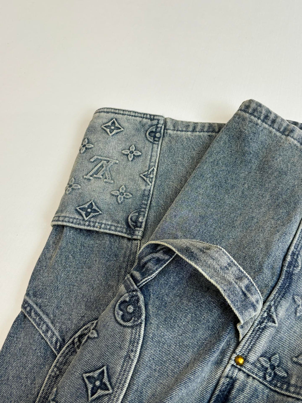 Blue denim pants with embroidered symbols on waistband and button fly