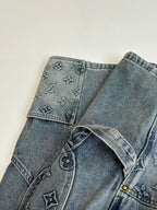 Blue denim pants with embroidered symbols on waistband and button fly