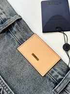 Denim shorts detail with tan leather tag and belt loops near the waist