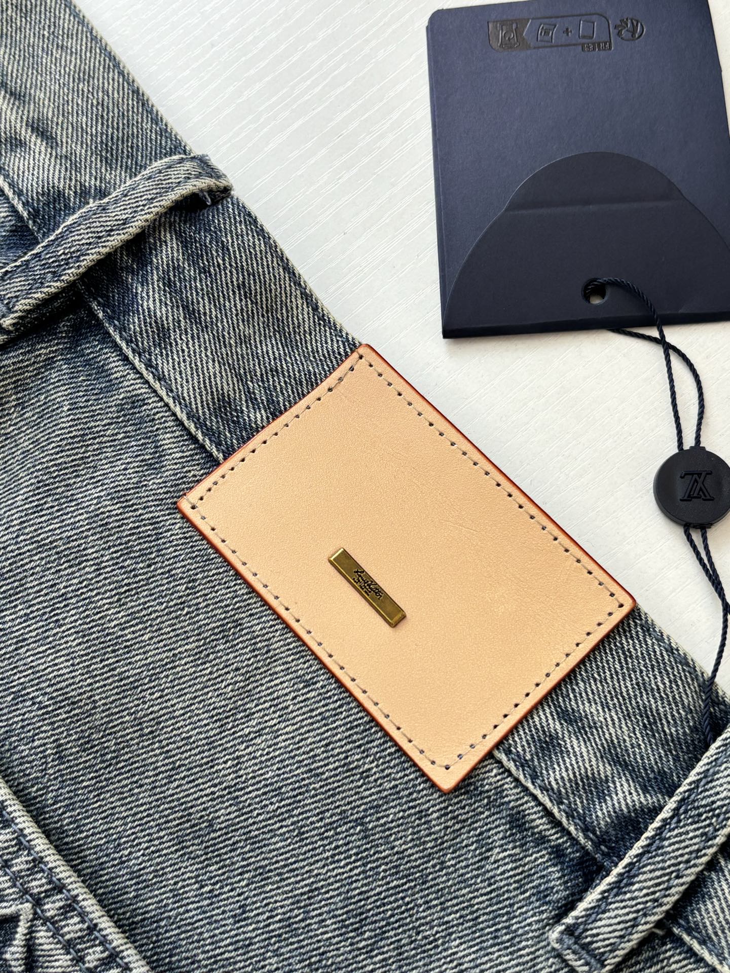 Denim shorts detail with tan leather tag and belt loops near the waist