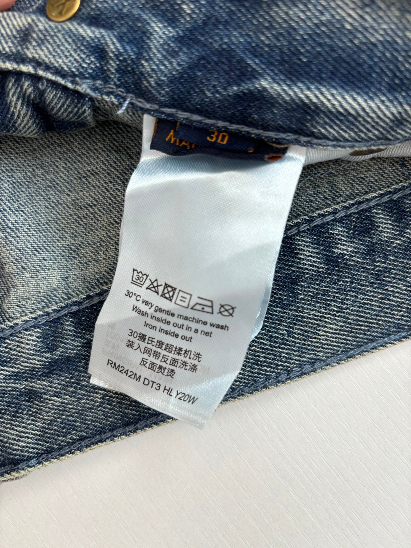 Denim pants care label inside waistband with washing instructions