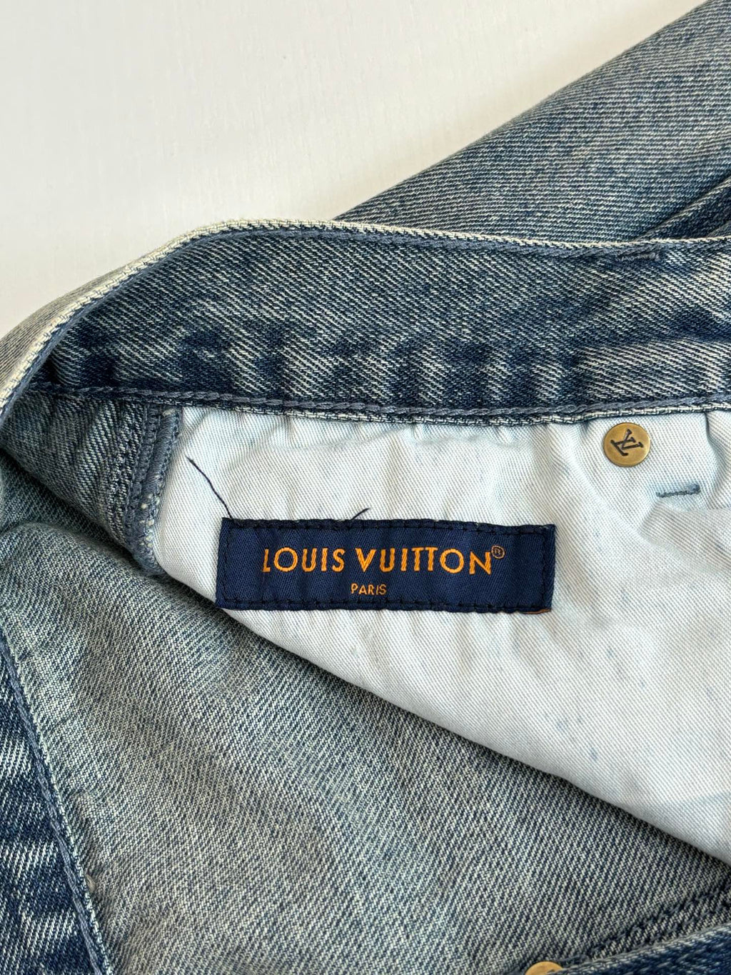 Louis Vuitton denim pants waistband with “LOUIS VUITTON” label and button