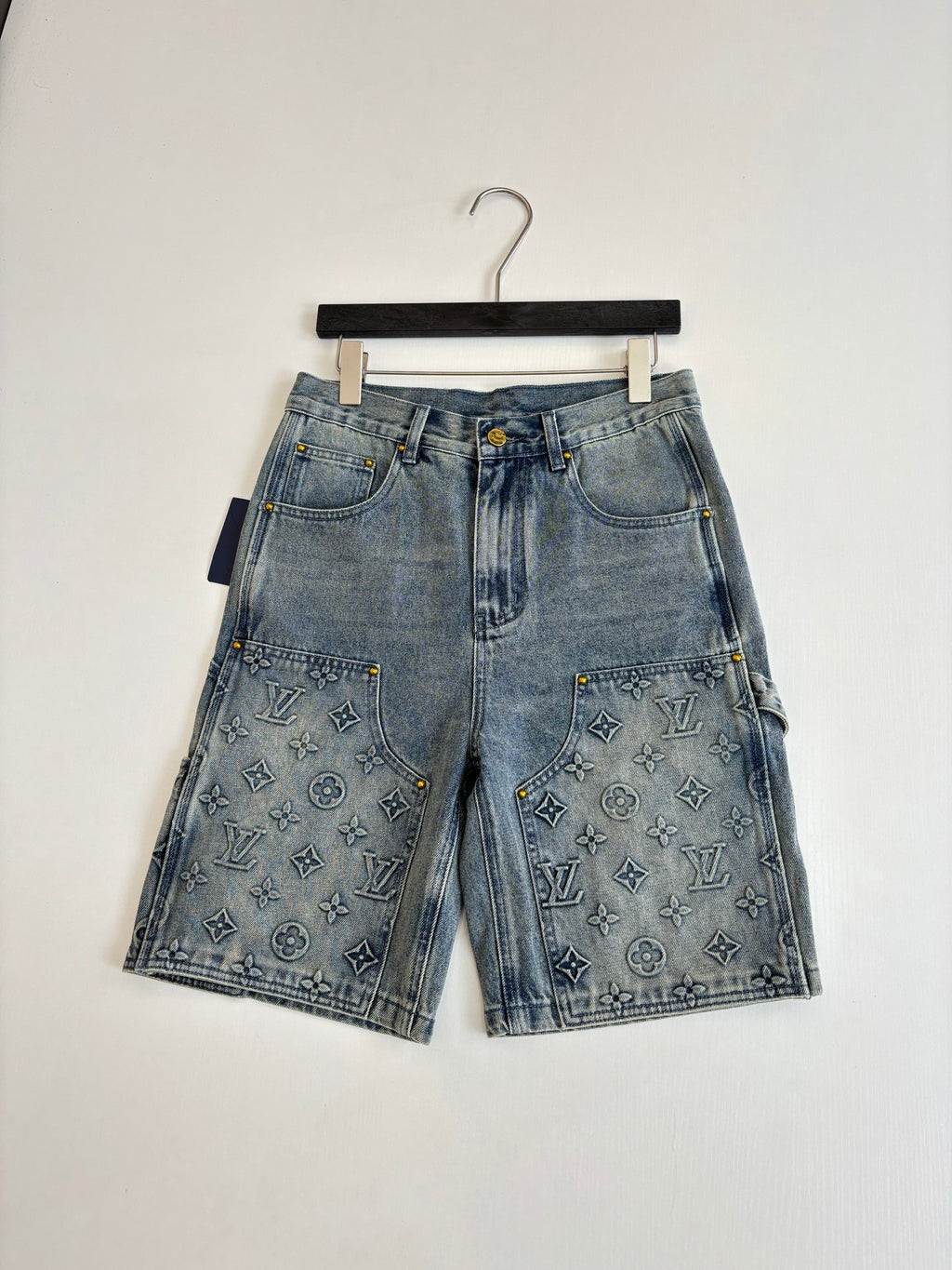 Light blue denim shorts on hanger with front button and monogram-print pockets
