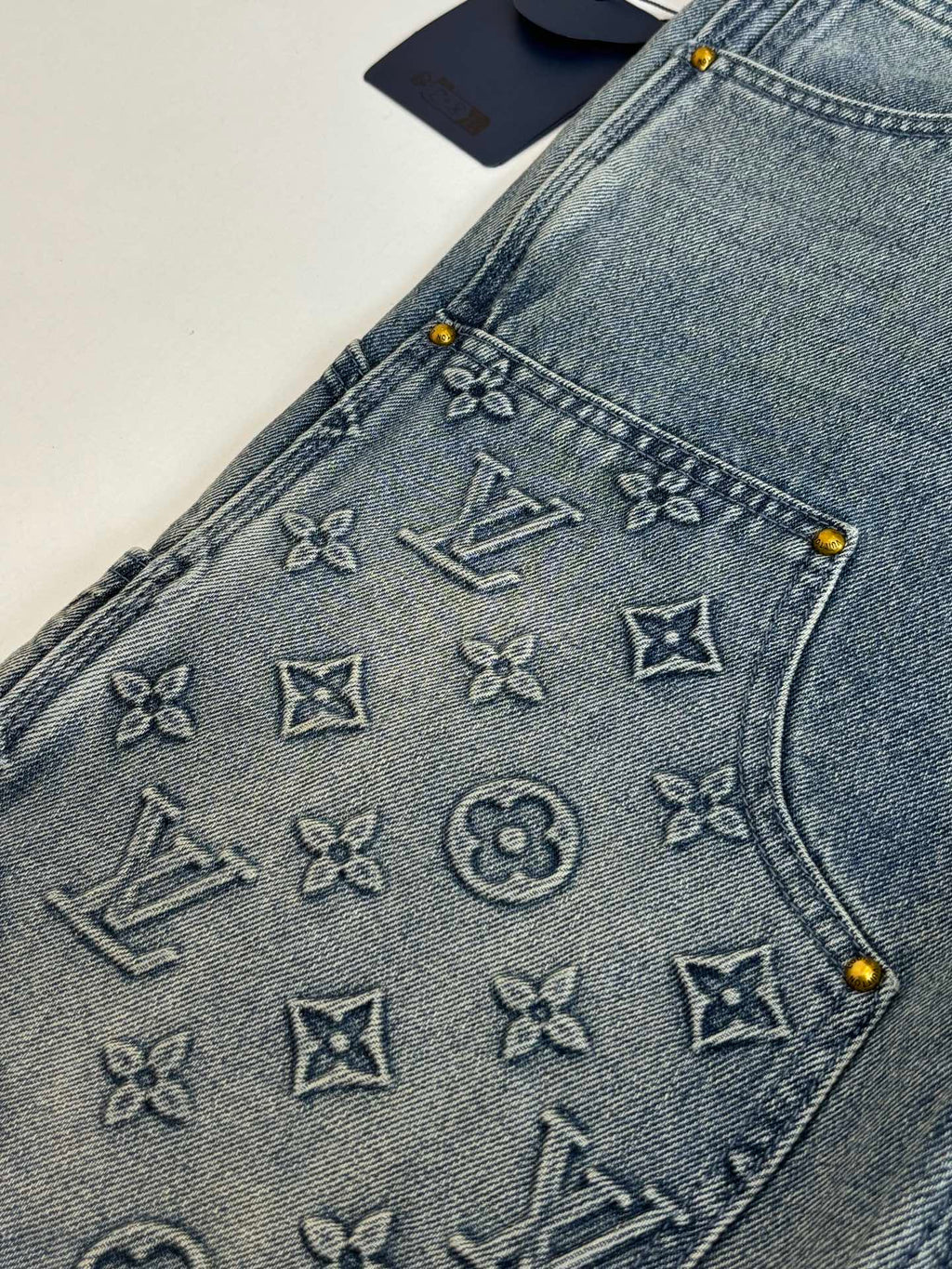 Denim shorts with embossed monogram symbols on the front pocket panel