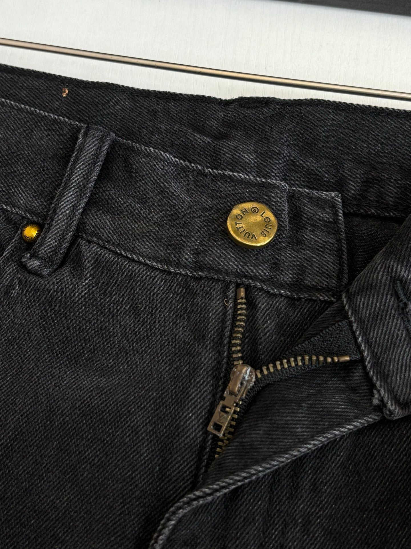 Dark denim shorts waistband detail with gold button and front zipper