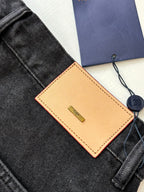 Brown leather Louis Vuitton tag and navy hang tag on dark denim shorts