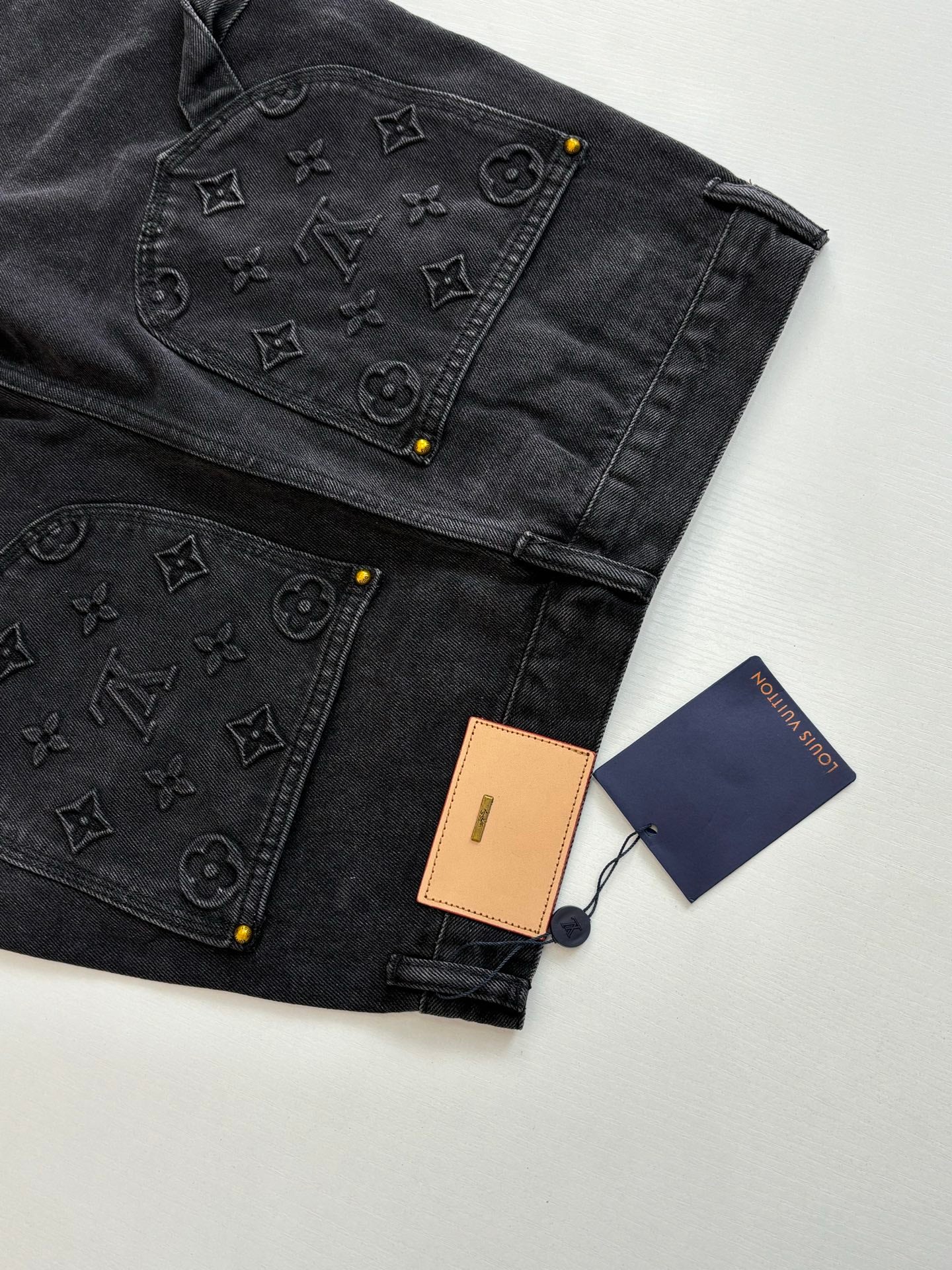 Dark denim Louis Vuitton shorts with monogram patchwork and hanging brand tags