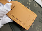 Louis Vuitton leather luggage tag in tan with gold stitching on dark green tote