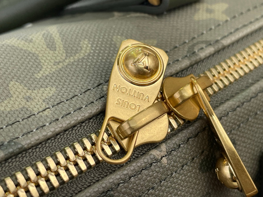 Louis Vuitton zipper pull and teeth close-up on dark green monogram fabric