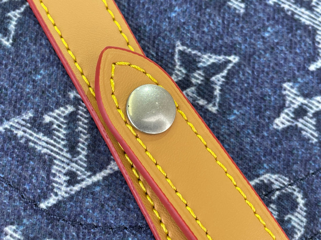 Tan leather strap tab with round metal snap on Louis Vuitton monogram canvas