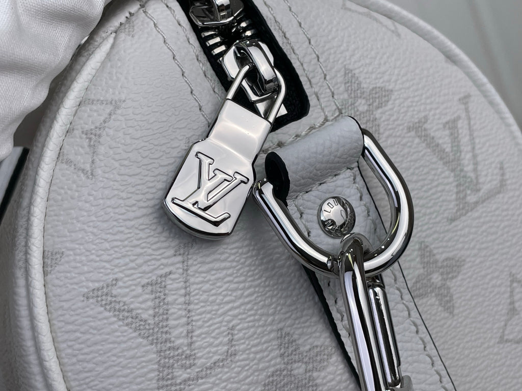 Close-up of white Louis Vuitton monogram bag hardware, D-rings, and keyring charm