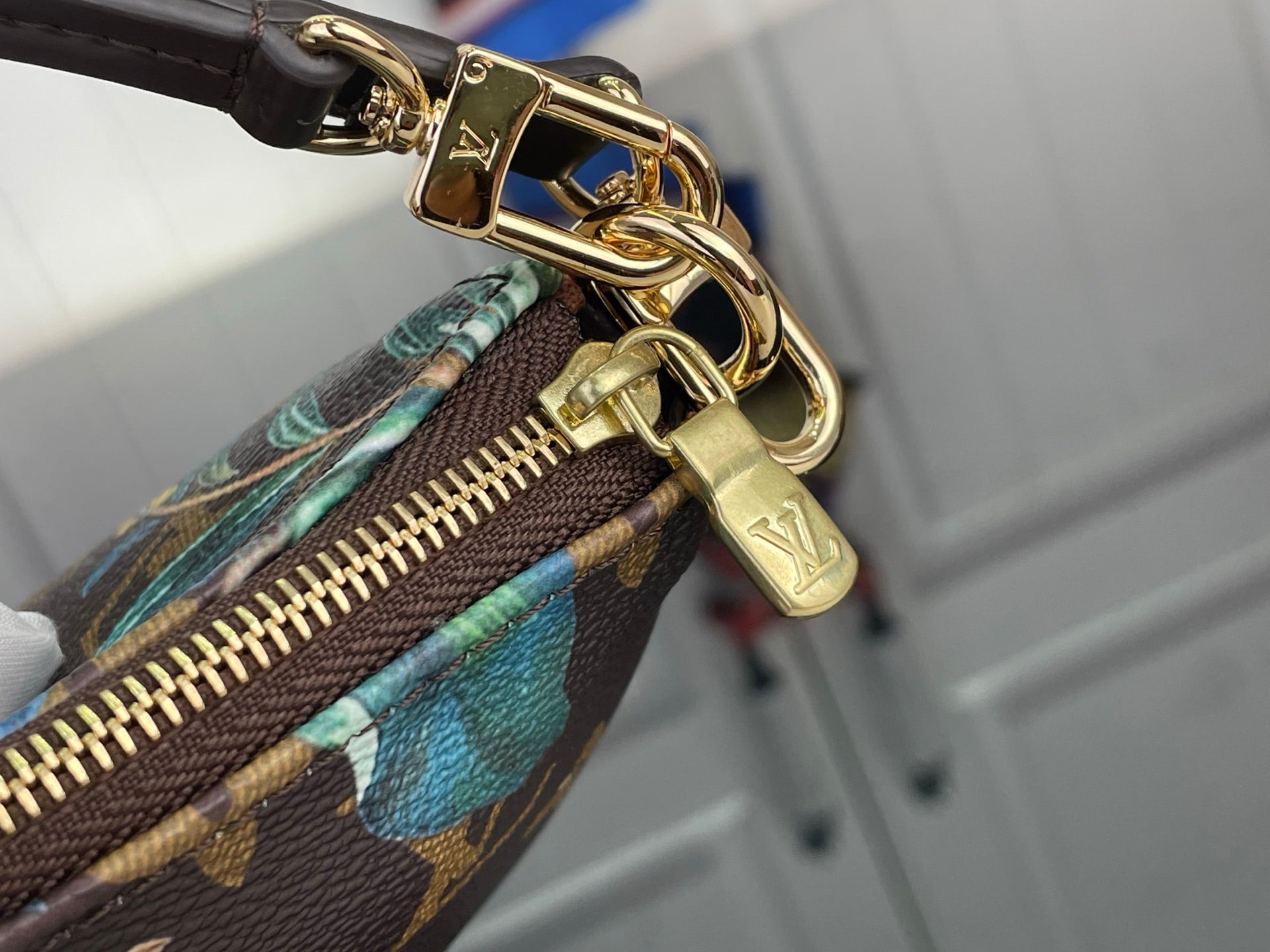 Gold-tone zipper and link hardware on printed crossbody bag