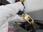 Gold-tone clasp and ring detail on dark leather crossbody strap