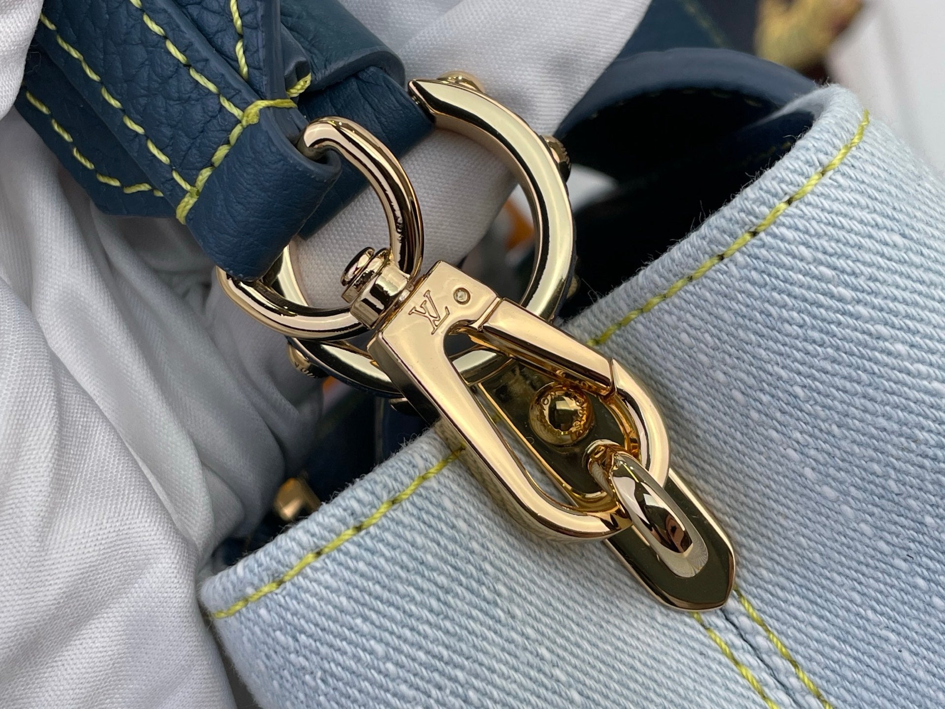 Gold-tone clasp hardware on light-blue interior lining of a two-tone satchel