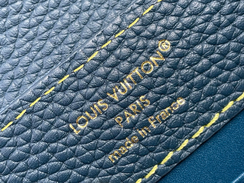 Blue pebble-grain leather with embossed Louis Vuitton Paris text and yellow edge stitching