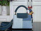 Two-tone handbag with top handle, blue front pocket, and gold-tone hardware