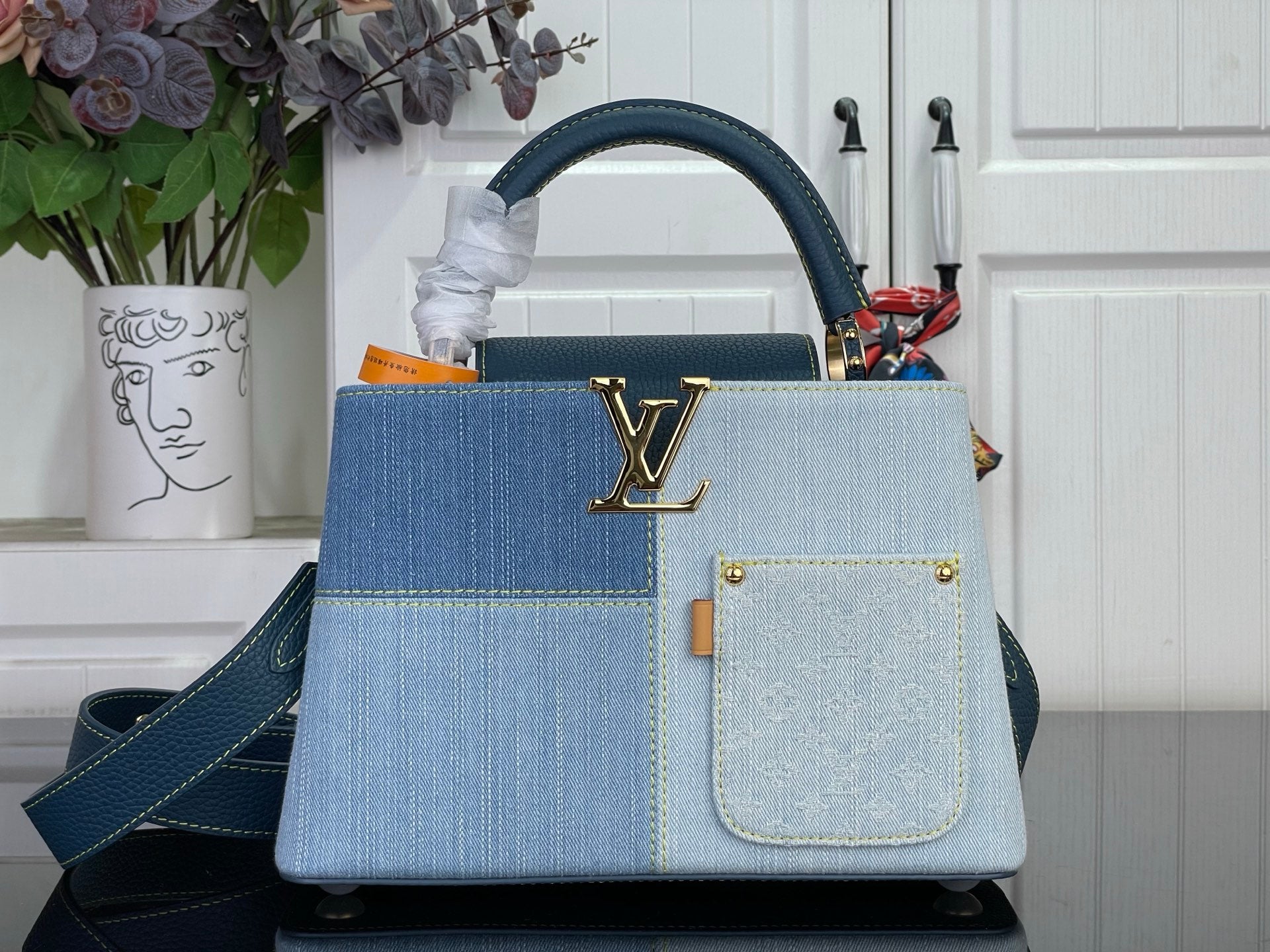 Louis Vuitton denim-look handbag with blue handles and gold LV emblem, strap