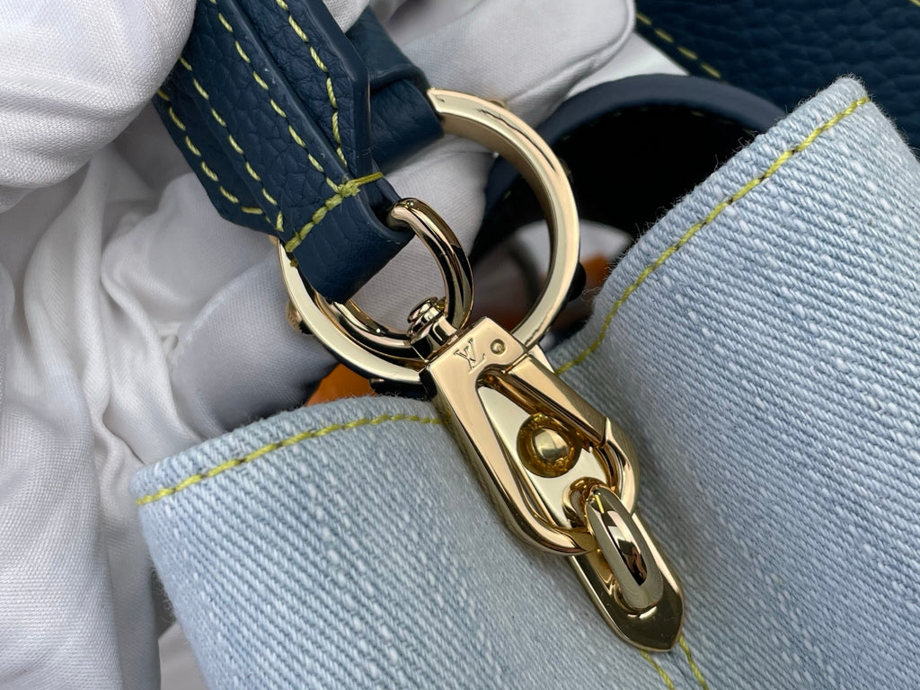 Gold chain clasp and ring hardware on blue denim-look handbag with yellow stitching