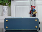 Blue textured handbag with gold corner studs and top handle, exterior close-up