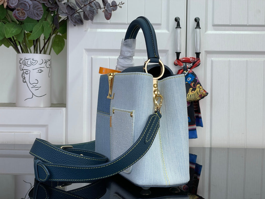 Louis Vuitton denim-look handbag with navy crossbody strap and gold hardware, light blue