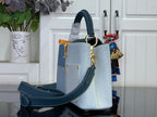 Louis Vuitton denim-look handbag with navy crossbody strap and gold hardware, light blue