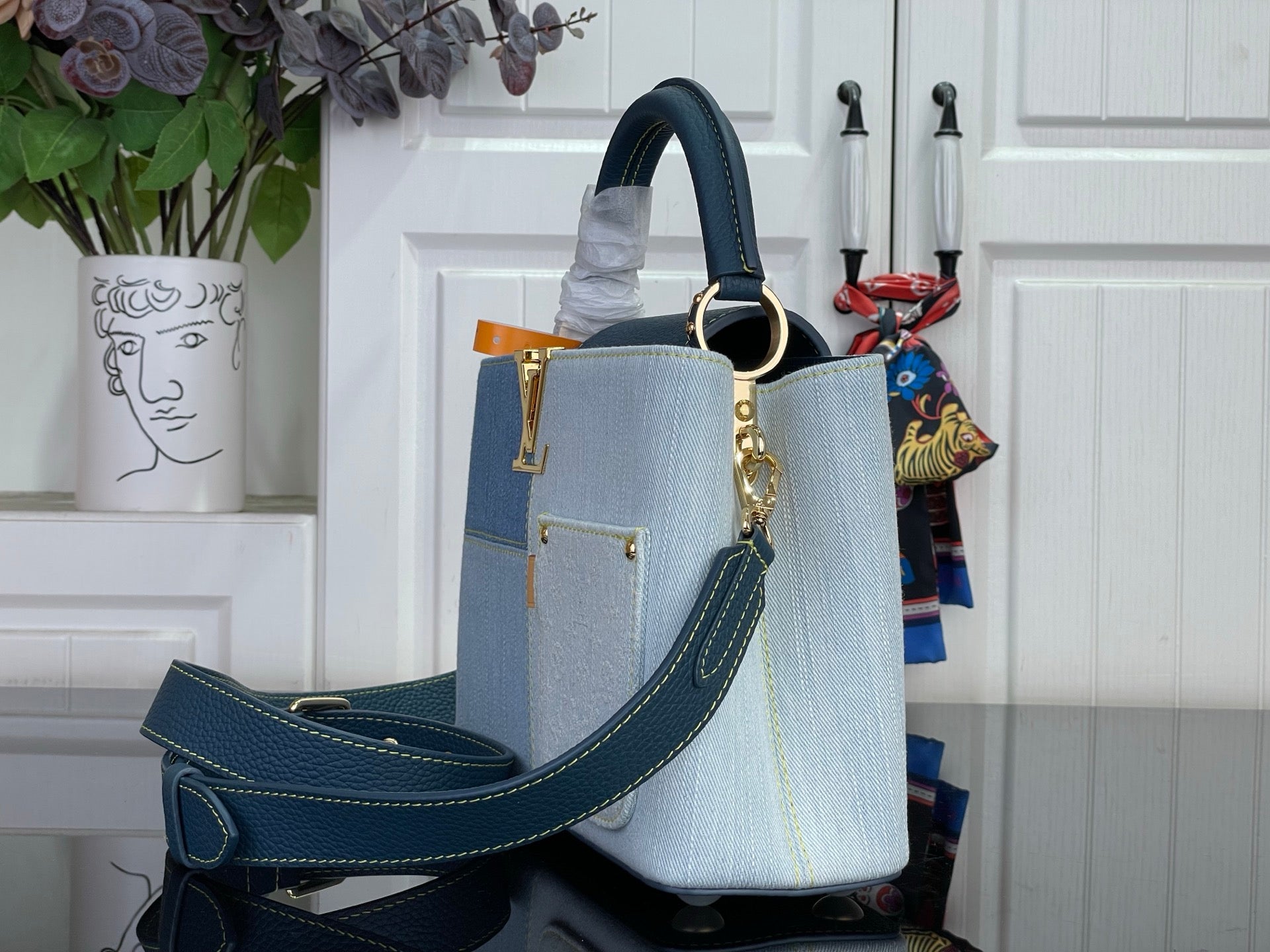 Louis Vuitton denim-look handbag with navy crossbody strap and gold hardware, light blue