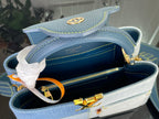 Blue denim-look handbag open with dark lining, gold zipper and clasp hardware