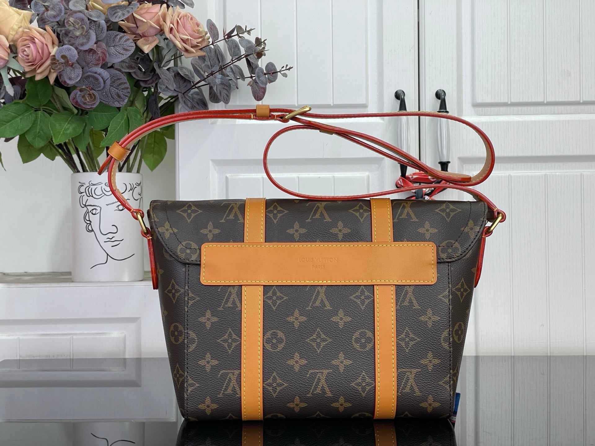 Monogram crossbody bag with tan center panel and red top handle, side view