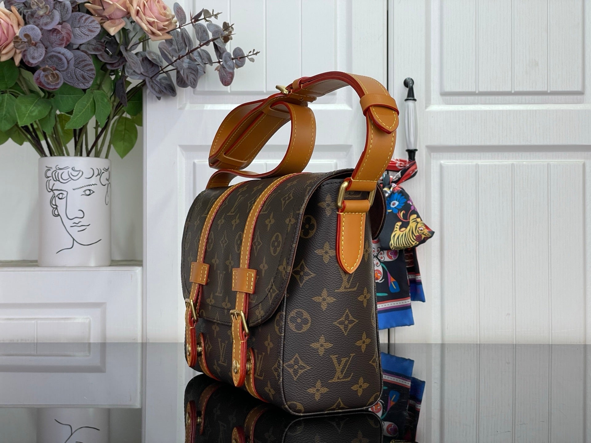 Monogram shoulder bag with tan strap, colorful hanging charm, side angle