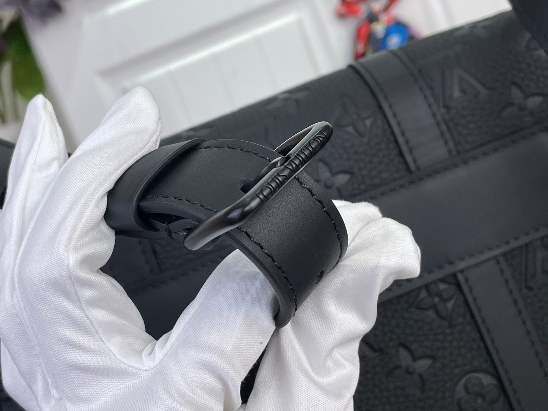 Louis Vuitton monogram bag close-up of dark strap and button closure on leather