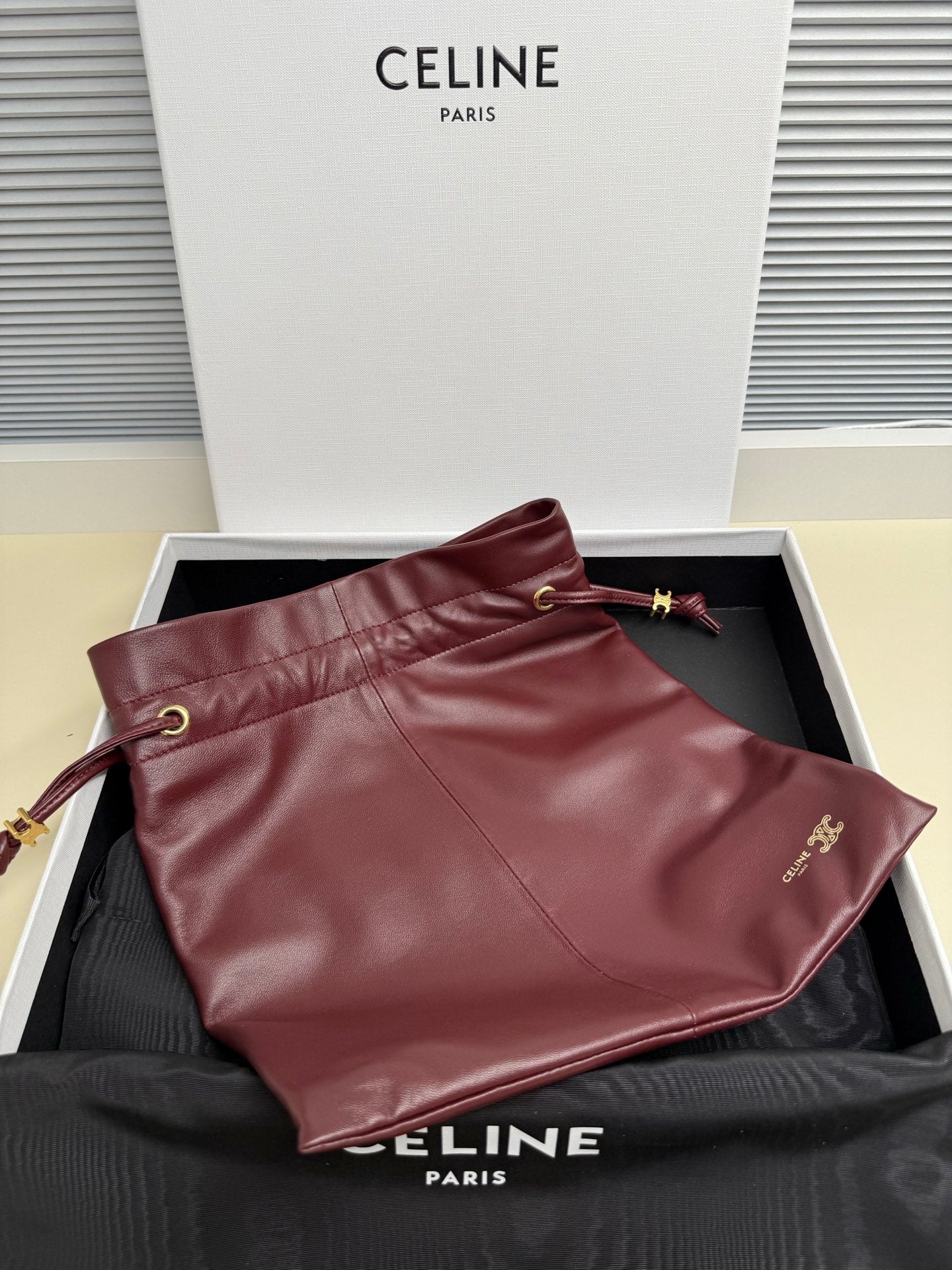 Burgundy leather drawstring pouch with strap and small logo accent