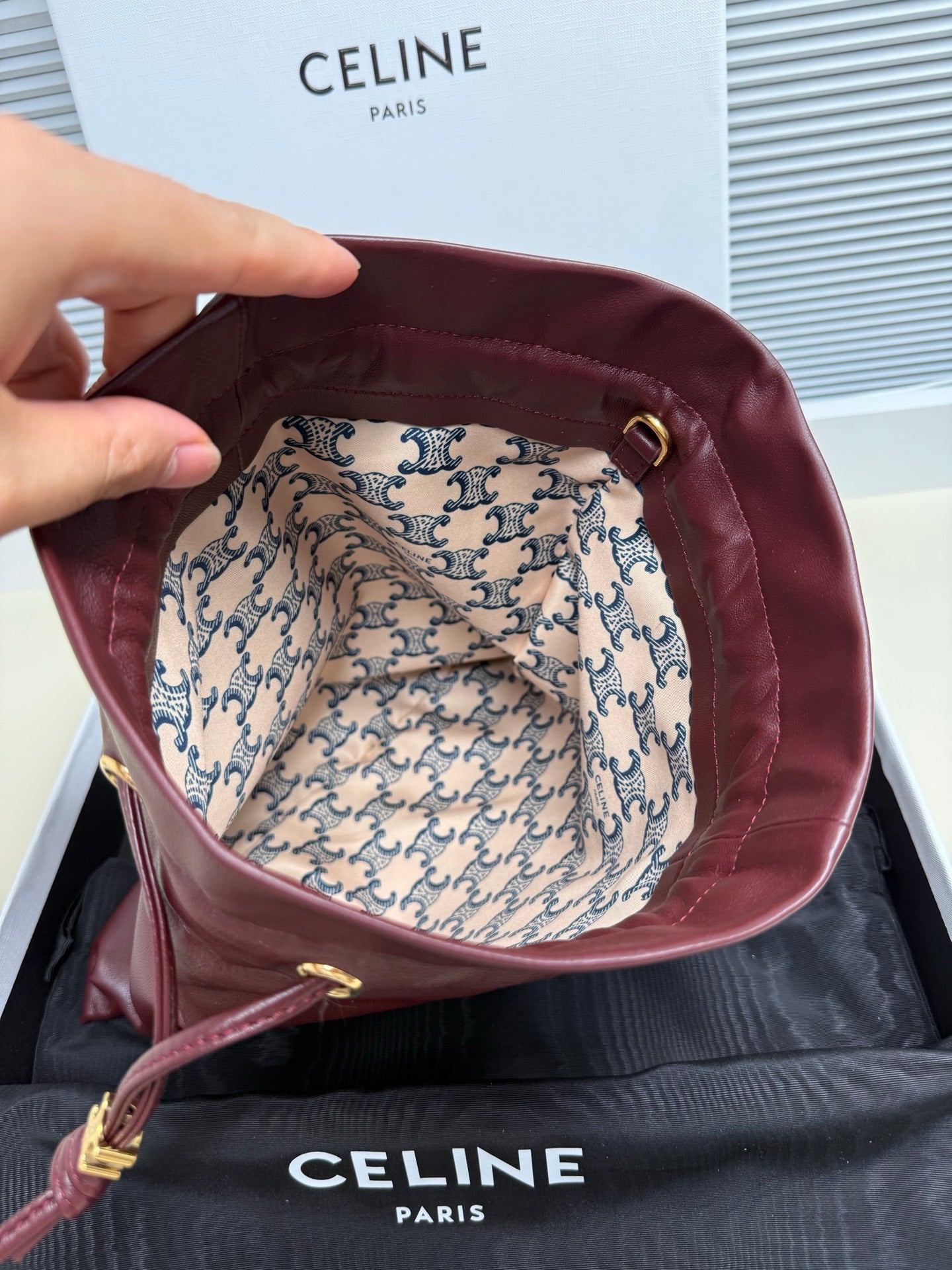 Open burgundy leather drawstring bag showing patterned fabric lining