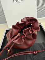 Burgundy leather drawstring bag with gathered opening and long cord straps