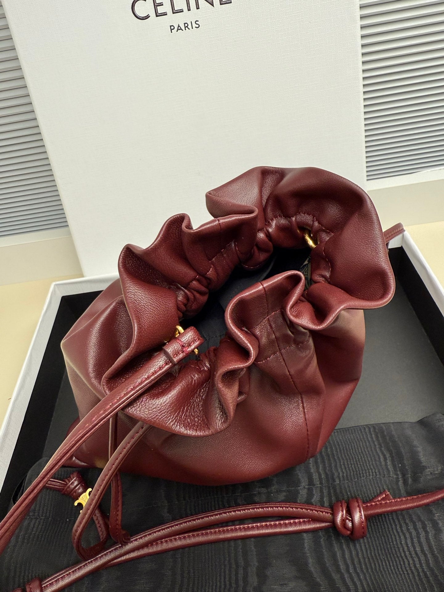 Burgundy leather drawstring bag with gathered opening and long cord straps