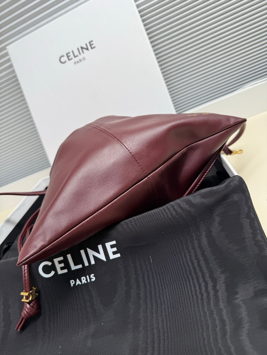 Burgundy leather drawstring bag side profile with cord strap and gold hardware