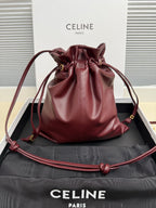 Burgundy leather drawstring bag with gathered top and gold-tone hardware