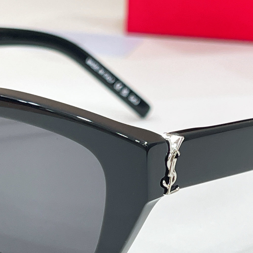 Close-up of black sunglasses hinge and dark lens with temple arm branding