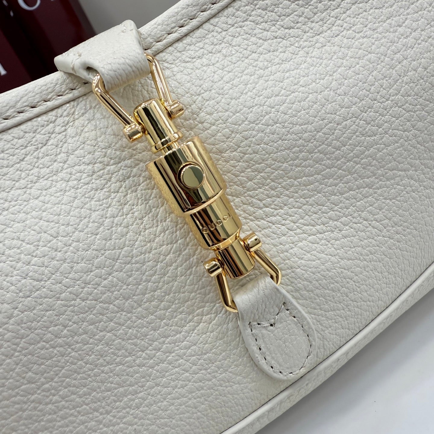 Gucci white leather bag close-up of gold-tone lock hardware and stitching