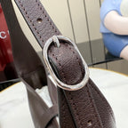 Dark leather hobo bag strap detail with metal O-ring and stitched connection point