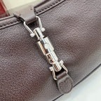 Dark leather hobo bag clasp close-up with silver-tone hardware and stitched edge