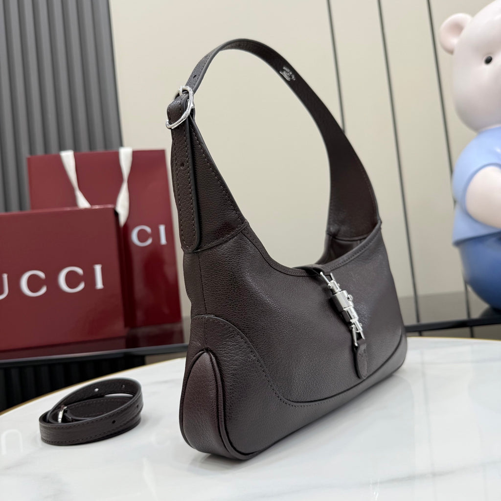 Dark leather hobo bag side view with curved handle and hanging strap accessory