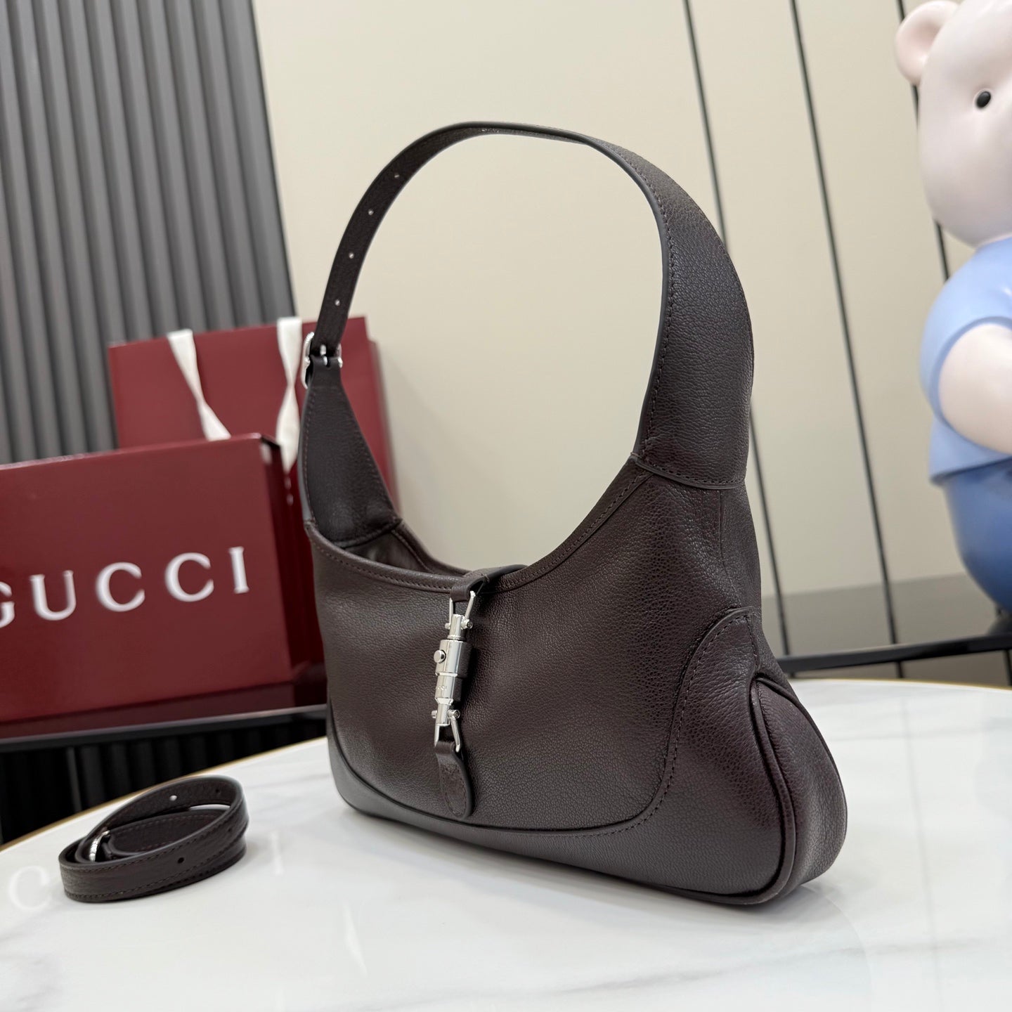 Dark leather hobo bag angled view with curved handle and central clasp