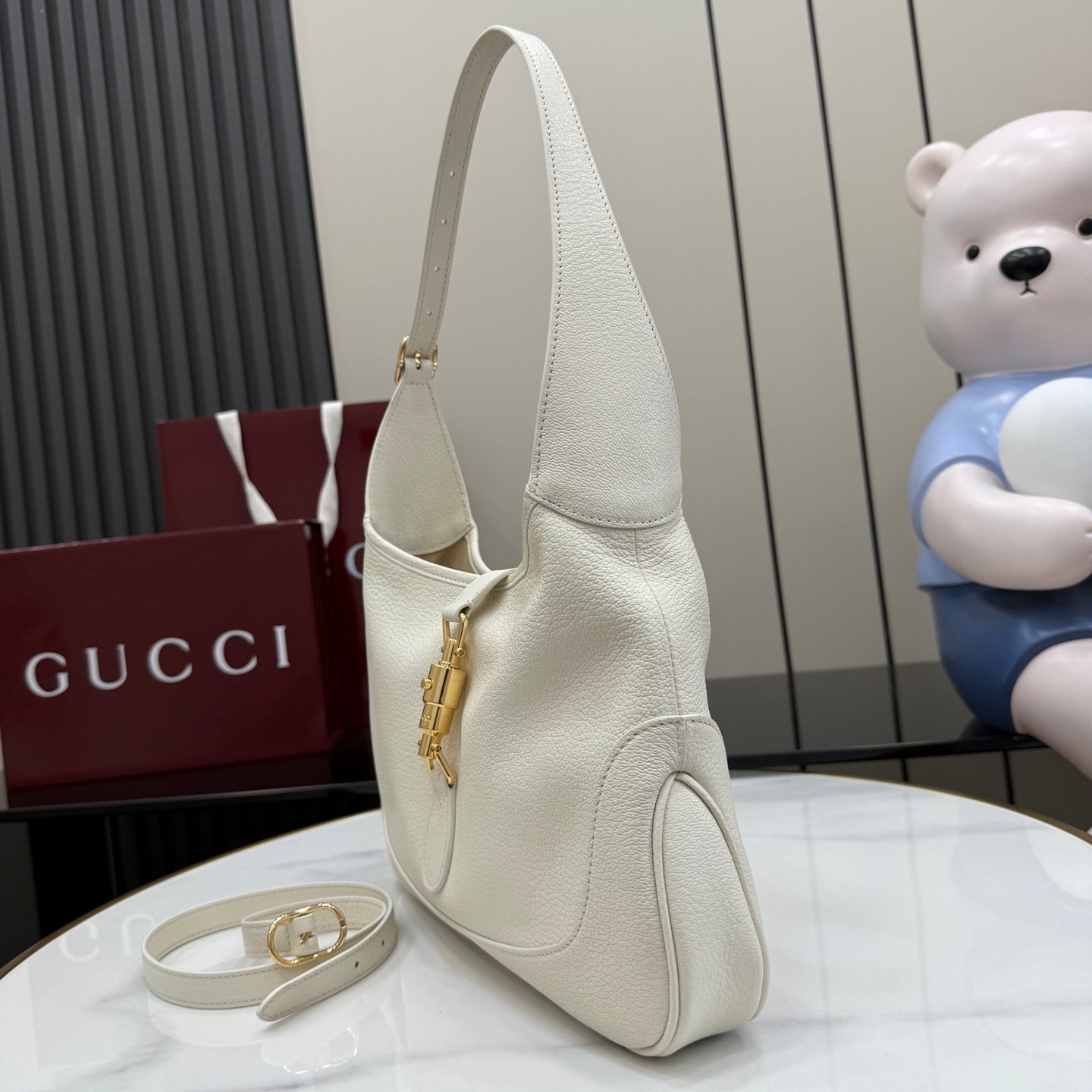 White leather hobo bag angled view with gold zipper detail
