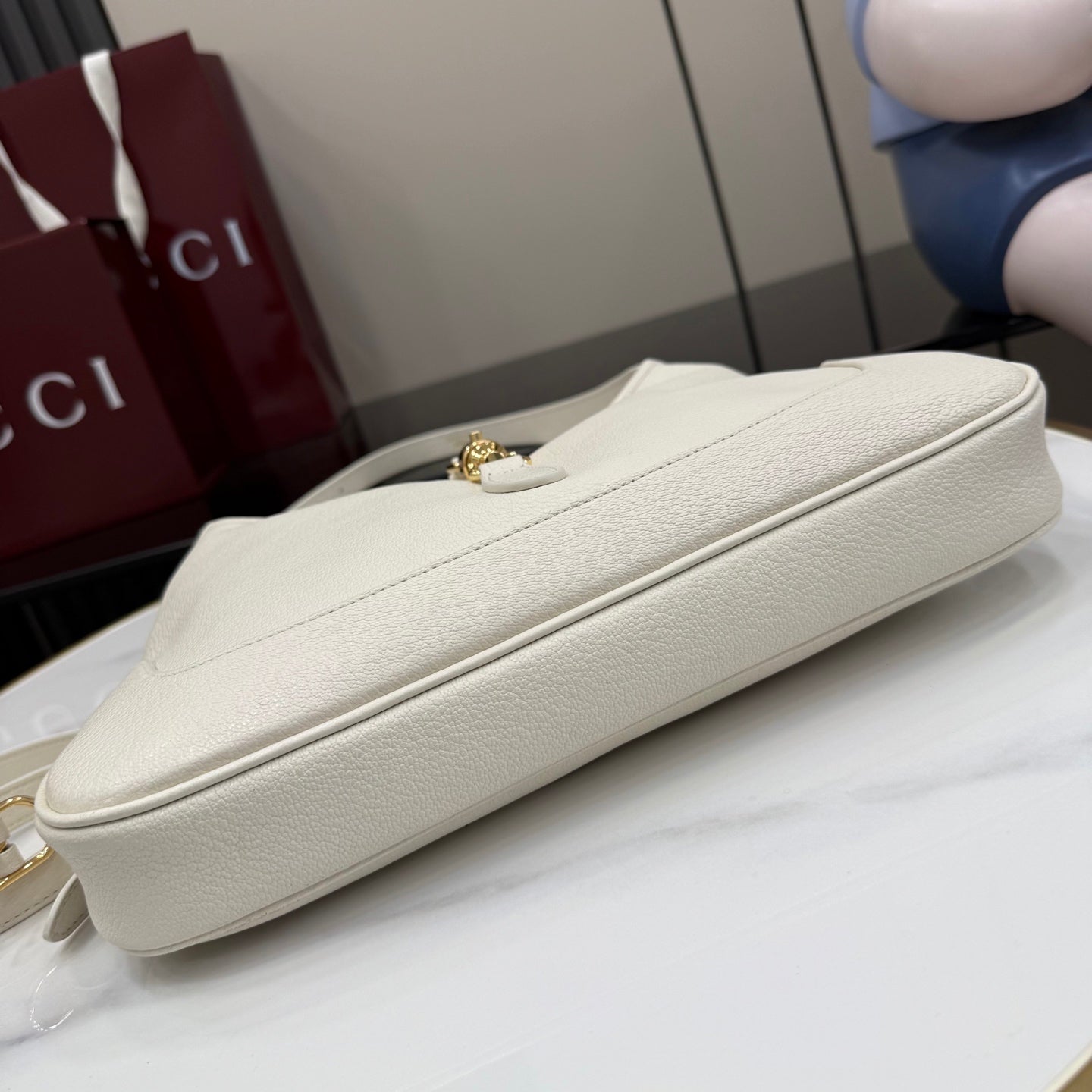 White leather clutch-style bag with gold clasp on top