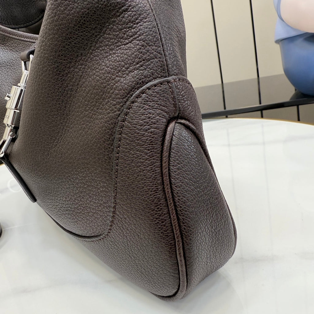 Pebbled leather handbag, dark side view with zipper pull and curved panel