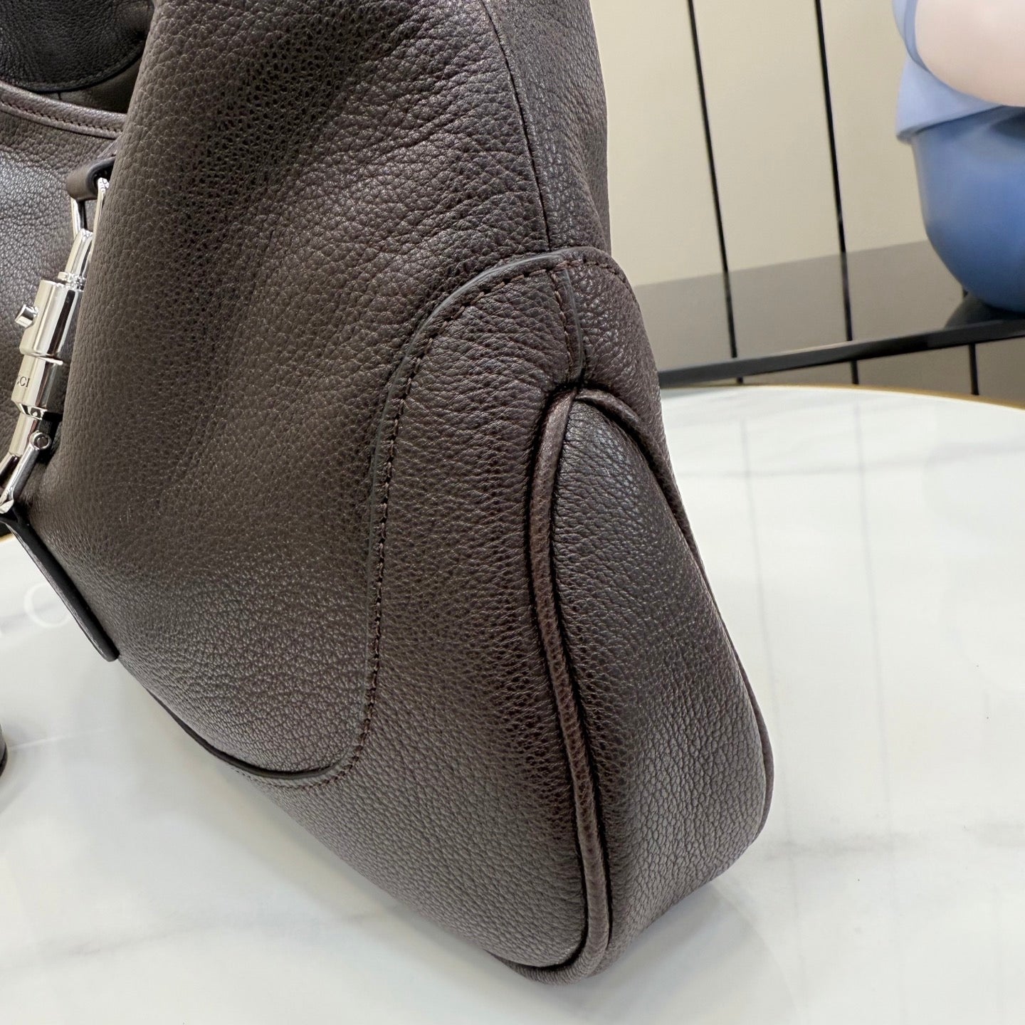 Pebbled leather handbag, dark side view with zipper pull and curved panel